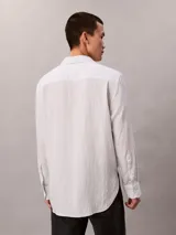 Camisa de manga larga Calvin Klein con diseño de rayas finas verticales, cuello camisero y cierre frontal de botones.