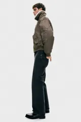 Campera bomber de nylon color marrón, ligeramente acolchada, con cuello de peluche blanco y cierre frontal. Incluye un bolsillo con cierre en una manga, bolsillos laterales con solapa y botón a presión oculto, y un bolsillo interior con botón a presión. Tiene remate acanalado ancho en puños y bajo, y un corte holgado.