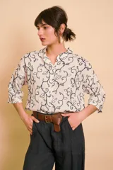 Camisa blanca de manga larga con cuello mao y estampado de motivos vegetales en tono azul oscuro.