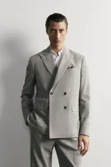 Blazer regular fit de Zara, confeccionada en tejido con mezcla de lana y algodón con diseño de cuadros grises. Cuenta con solapas de pico, doble botonadura cruzada, bolsillos con solapa en la cadera y bolsillo de vivo en el pecho.