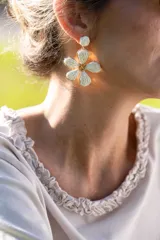 Aros colgantes en forma de flor con pétalos de rafia blanca y centro dorado.