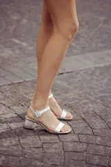 Sandalia de tacón cuadrado bajo, color plateado, con tira frontal y tira ajustable al tobillo con hebilla.
