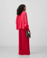 Camisa amplia semitransparente color blanco, con cuello chimenea y manga japonesa con puño. Presenta botonadura frontal oculta por solapa.