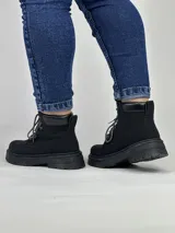 Borcego negro de caña baja con suela track y cordones combinados en blanco y negro.