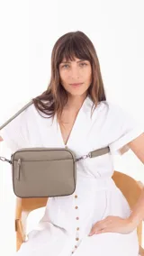 Bandolera color bordó con diseño texturizado geométrico en el frente, bolsillo frontal con cierre, bolsillo trasero con cierre y compartimento principal con divisiones. Incluye correa extensible.