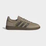 Zapatillas Adidas Handball Spezial de corte bajo, con parte superior de ante en tono beige claro y tres franjas laterales en verde oliva. Presentan puntera en T y suela de goma color café. La inscripción "SPEZIAL" se encuentra en el lateral en color oscuro.