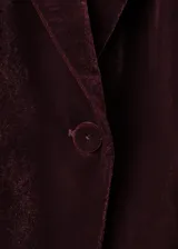 Blazer de terciopelo color bordó, con solapas con muesca, cierre frontal de un botón, bolsillos laterales con solapa y mangas largas con puños abotonados.