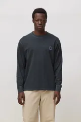 Remera de manga larga color gris oscuro con efecto lavado, cuello redondo y detalle de parche pequeño con logo en forma de X en el pecho.
