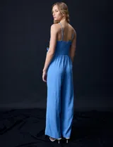 Enterito azul celeste de crepe, con escote cruzado en V, cintura elastizada y pierna ancha. Los tirantes son de cadena metálica.