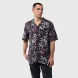 Camisa de manga corta con cuello cubano, confeccionada en viscosa con estampado botánico de hojas en tonos grises, blancos y violetas sobre fondo negro.
