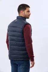 Chaleco reversible capitoneado de corte estándar, con cuello alto, cierre frontal de cremallera y botones a presión. Cuenta con bolsillos laterales y un bolsillo vertical en el pecho.