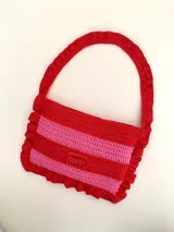 Cartera tipo shoulder bag tejida a crochet en hilo de algodón, con diseño a rayas en tonos de rojo y rosado, y detalles de volados en los bordes y la manija de hombro.