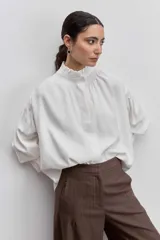 Camisa azul de manga larga con cuello alto fruncido y puños elásticos.