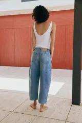 Jeans de tiro medio con pernera holgada tipo barrel que se estrecha hacia el tobillo, acabado con bajo sin costura, bolsillos delanteros y bolsillos de plastrón en la espalda. Cierre frontal con cremallera y botón.
