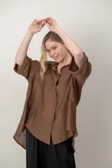 Camisa oversize de seda negra, con cuello camisero, cierre frontal con botones y mangas cortas con vuelta.