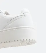 Championes blancos de caña baja con cordones, recortes laterales, puntera redonda y suela texturizada de 4cm de altura.