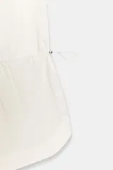 Mono corto de color blanco, confeccionado en mezcla de algodón y poliamida, con escote redondo, tirantes y cintura ajustable mediante cordón con stopper.