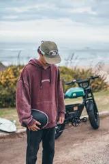 Hoodie de corte boxy fit en color bordó con efecto lavado. Presenta una estampa gráfica en la espalda con motivos playeros, palmeras y el texto 'Classy Waves'.