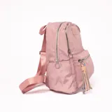 Mochila rosa de tela con cierre superior y bolsillo frontal con cierre. Tiene correas ajustables y un llavero decorativo.