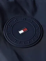 Campera bomber azul marino de poliéster reciclado, con cuello estilo béisbol, cierre de cremallera, puños y cuello de punto canalé, dos bolsillos diagonales en la cintura y detalles distintivos de Tommy Hilfiger.