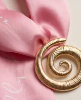 Pañuelo de seda con diseño estampado en tonos rosados y rojos, combinado con un dije dorado en forma de espiral.