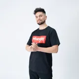 Remera de manga corta negra con logo Wrangler enmarcado en un rectángulo rojo en el pecho. Confeccionada en algodón.