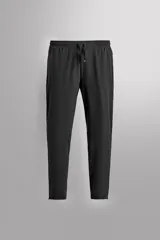 Pantalón negro de entrenamiento slim fit confeccionado en tejido técnico ligero y elástico con estructura. Cuenta con cintura elástica ajustable con cordón, bolsillos frontales y trasero con cierre de cremallera, y bajo ajustable con cremallera en laterales.