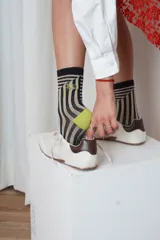 Medias de caña media con estampado de líneas onduladas en tonos beige y negro, talones y punteras en color verde lima y detalle de bordado en el lateral.