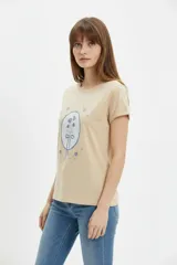 Remera de algodón color beige, de manga corta con vuelta, cuello redondo y estampa frontal de flores con lazo en tonos azules y celestes.