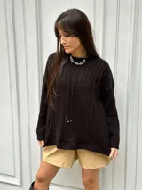 Sweater tejido color negro, con cuello redondo y diseño de ochos en el frente y mangas con diseño a rayas verticales.