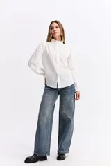 Blusa de algodón en color celeste, con textura sutil, cuello con volados y mangas largas con puños también decorados con volados. Presenta cierre frontal con botones.