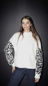 Sweater negro de punto con cuello alto y bordado blanco en las mangas.