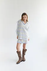 Chaleco tejido de lana con patrón de rombos en tonos lila, rojo y beige, con cuello en V y ribetes en color crema. Diseño oversize.