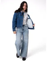 Chaqueta de jean azul con forro interior y cuello de sherpa blanco. Presenta cierre frontal con botones metálicos, bolsillos laterales y ajuste con botones en la cintura.
