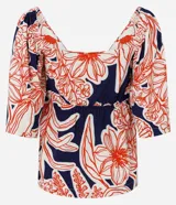 Blusa azul marino con estampado floral en tonos rojo y blanco, escote en pico con nudo y mangas cortas fruncidas.