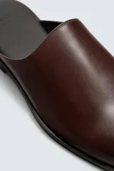 Zueco de cuero color marrón con forro y plantilla de cuero, horma cuadrada y suela con ligero tacón.