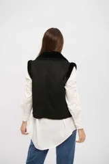 Chaleco negro de gamuza sintética con interior de piel sintética, diseño sin mangas y cierre frontal con botones.