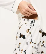 Pijama largo de dos piezas confeccionado en viscolycra. La blusa es de manga larga con cuello redondo y detalle de bies contrastante en el borde. El pantalón presenta un estampado floral y cintura elástica.