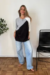 Remerón de manga tres cuartos con diseño de bloques de color en diagonal: gris claro en la parte superior izquierda, negro en la parte inferior derecha y blanco en la manga derecha. Posee cuello redondo y calce holgado.