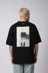 Remera oversize de algodón 100% premium, color blanco hueso, con bordado frontal "90's" en negro y un parche trasero con una imagen estilo videoclip de Nirvana.