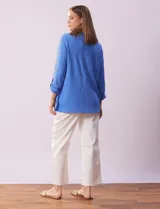 Camisa celeste de textura arrugada, con cuello clásico, cierre frontal con botones y mangas 3/4 con trabilla.
