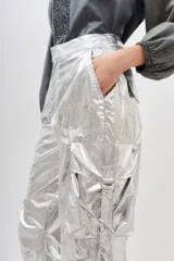 Pantalón cargo de poliamida plateado con efecto metalizado y acabado arrugado. Presenta cintura ajustable con lazo y puños ajustables en los tobillos.