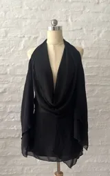 Vestido corto negro con escote halter, hombros descubiertos y mangas largas acampanadas.