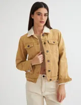 Campera de gabardina color mostaza, forrada con corderito color crudo en el cuerpo y cuello. Tiene corte clásico y botones metálicos personalizados.