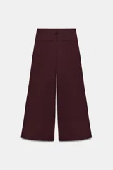 Pantalón de tiro medio con corte wide leg, presenta pliegues frontales, bolsillos laterales y trabilla con botón en la espalda. Cierre frontal con cremallera y botón.