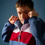 Buzo de felpa con medio cierre, diseño a bloques de color azul, blanco y rojo.