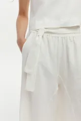 Pantalón palazzo de lino color blanco, de corte amplio con aberturas laterales, cintura elastizada con lazo ajustable y bolsillos.