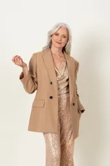 Blazer color beige de crepe de lana, con doble fila de botones negros.