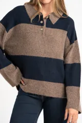 Sweater de punto con cuello polo y cierre frontal de tres botones. Presenta un diseño de corte oversize, mangas largas y textura acanalada.