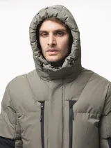 Campera puffer con capucha, de diseño bicolor en tonos gris topo y negro. Presenta cierre frontal con solapa de botones, bolsillos laterales y ajuste en los puños.